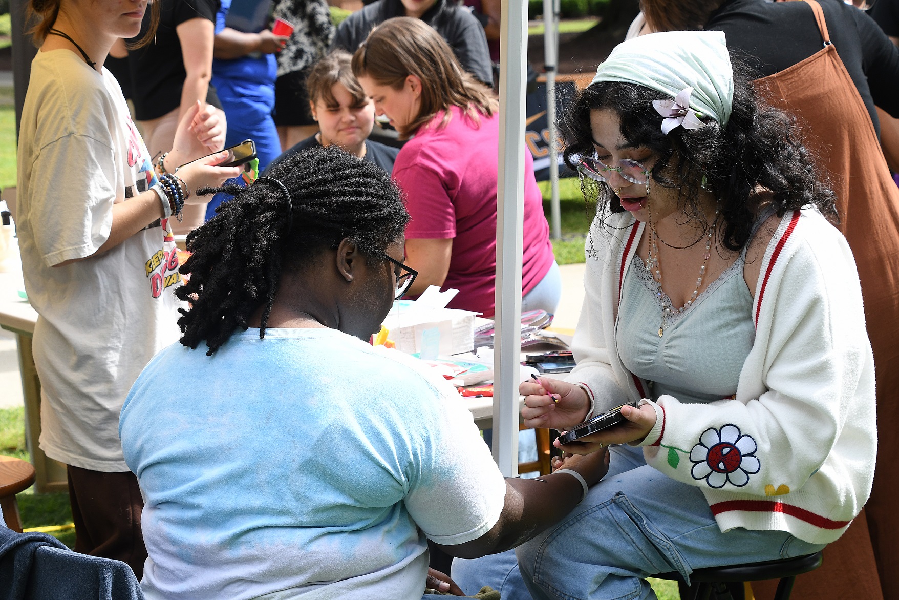 A student gets a decoration painted on her arm.
