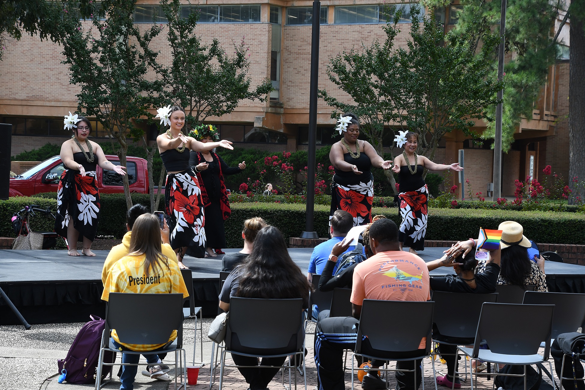 A group of dancers perform traditional hula in front of an audience.