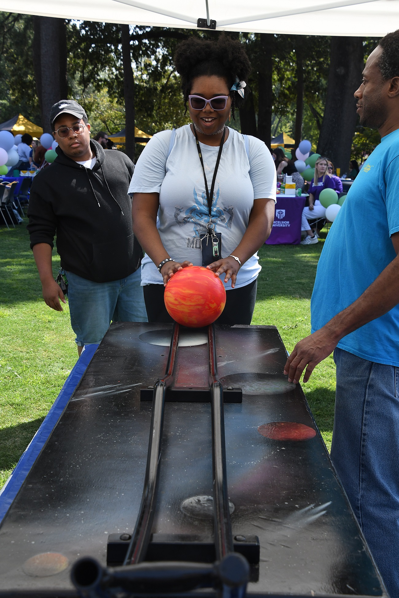 A student prepares to roll a bowling ball across a raised rail.