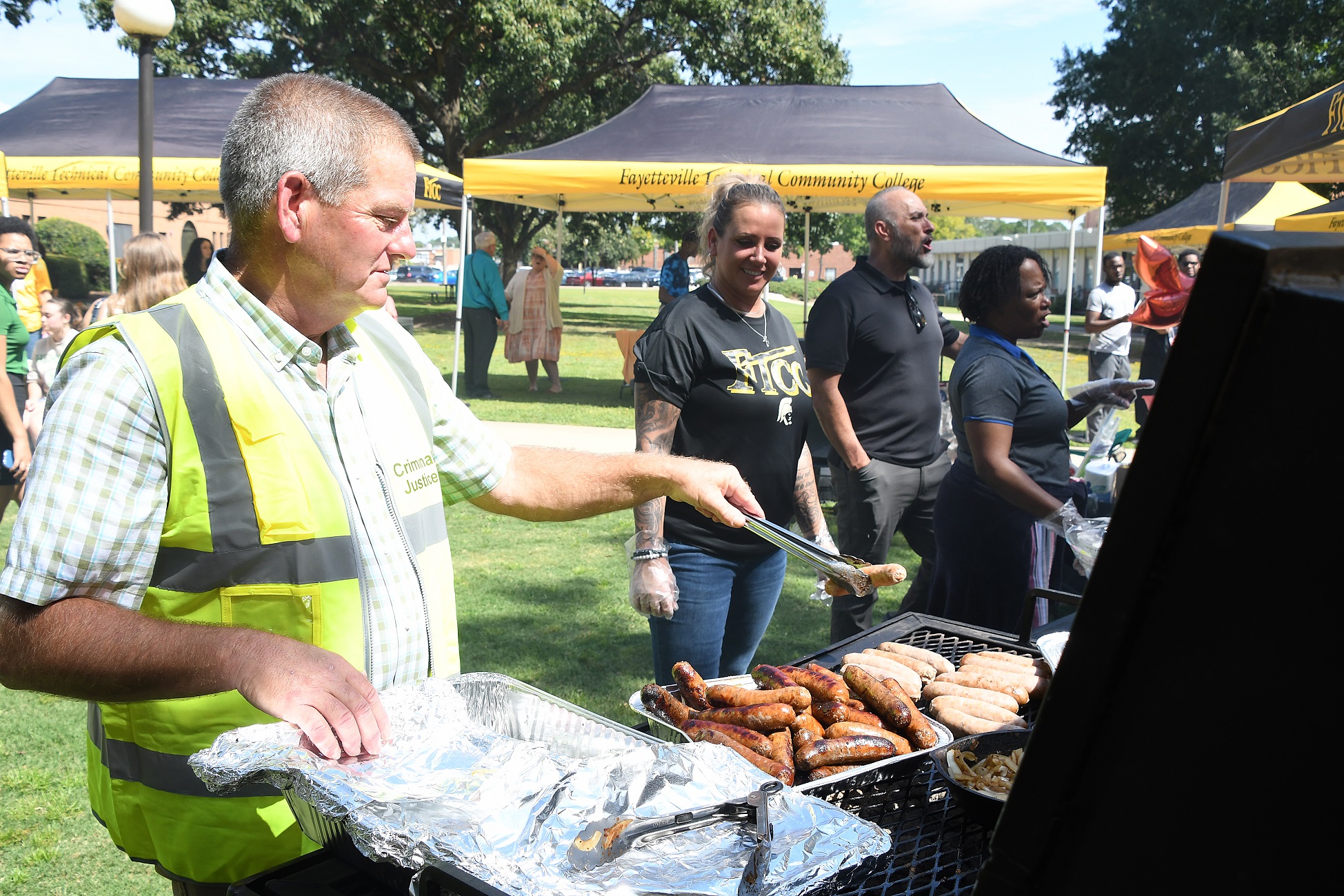 An instructor grills hot dogs.
