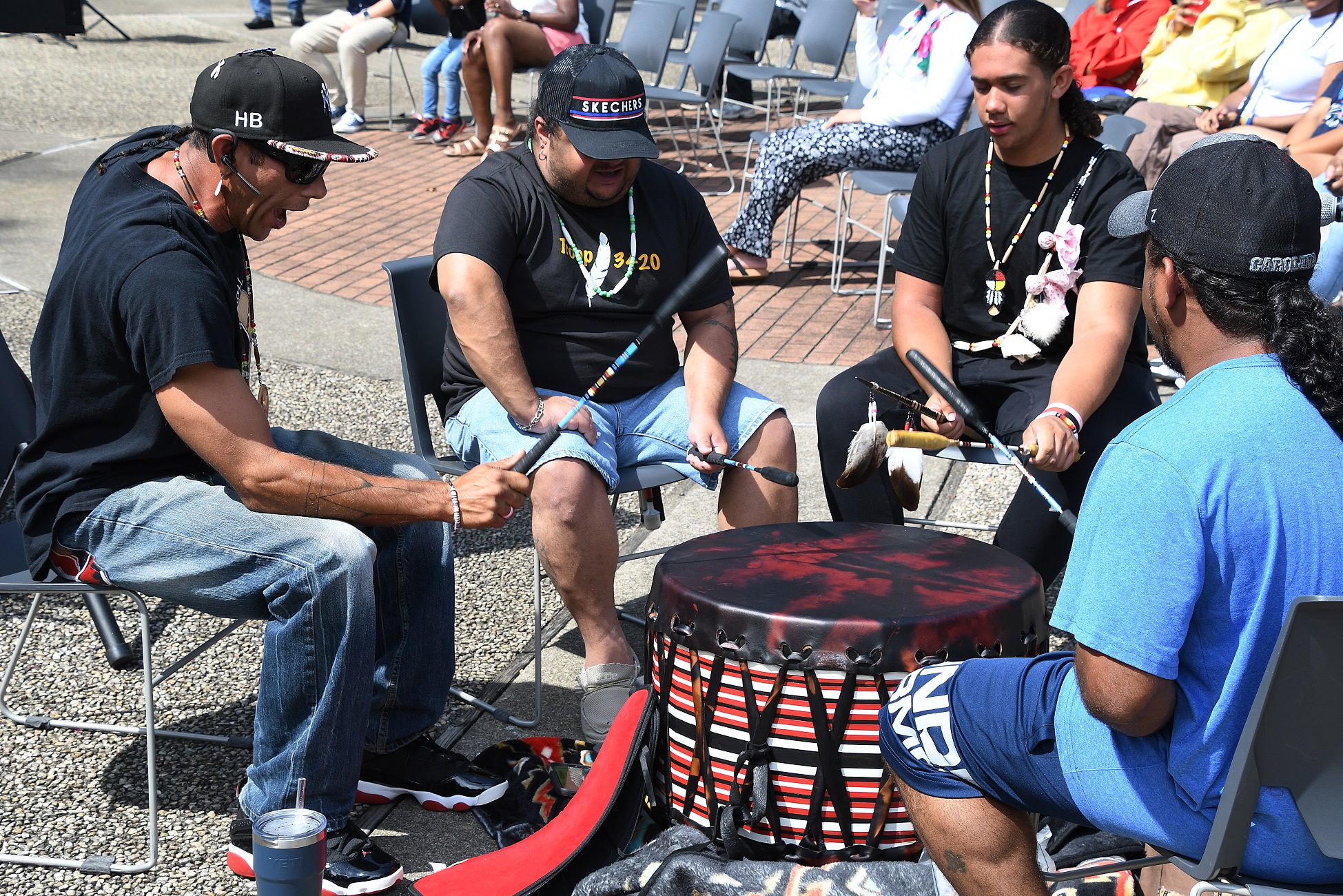 A group of musicians play a traditional Native American drum.
