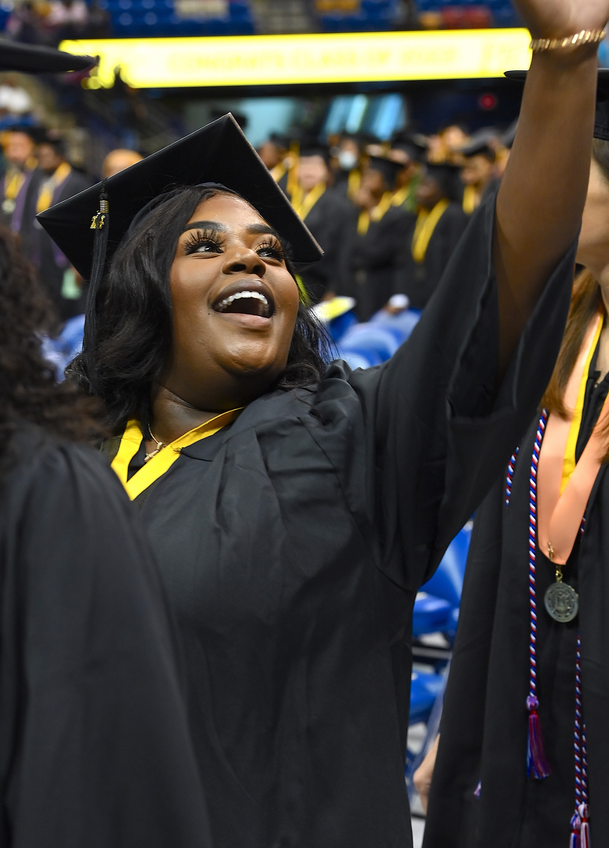 A graduate lifts her hand high to wave to the crowd.