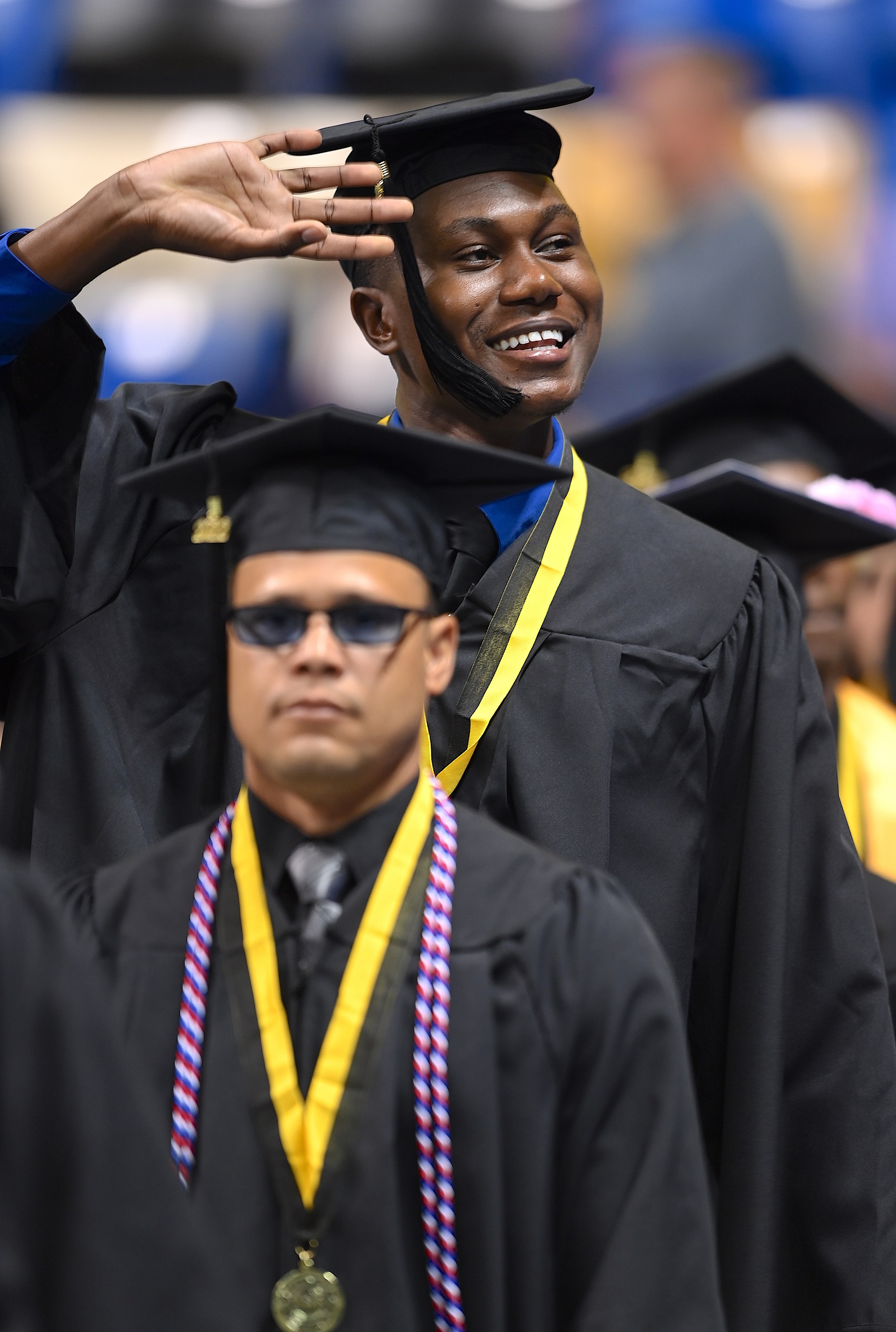 A tall graduate waves his hand to the crowd.