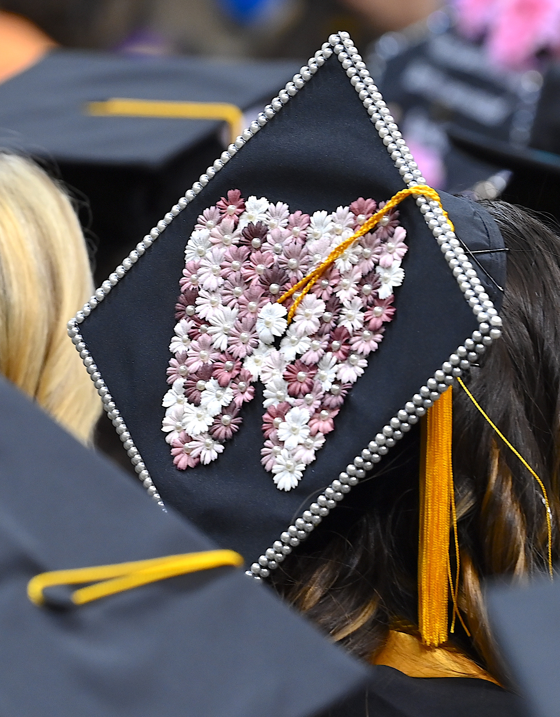 A graduation cap decorated with a tooth made out of buttons.