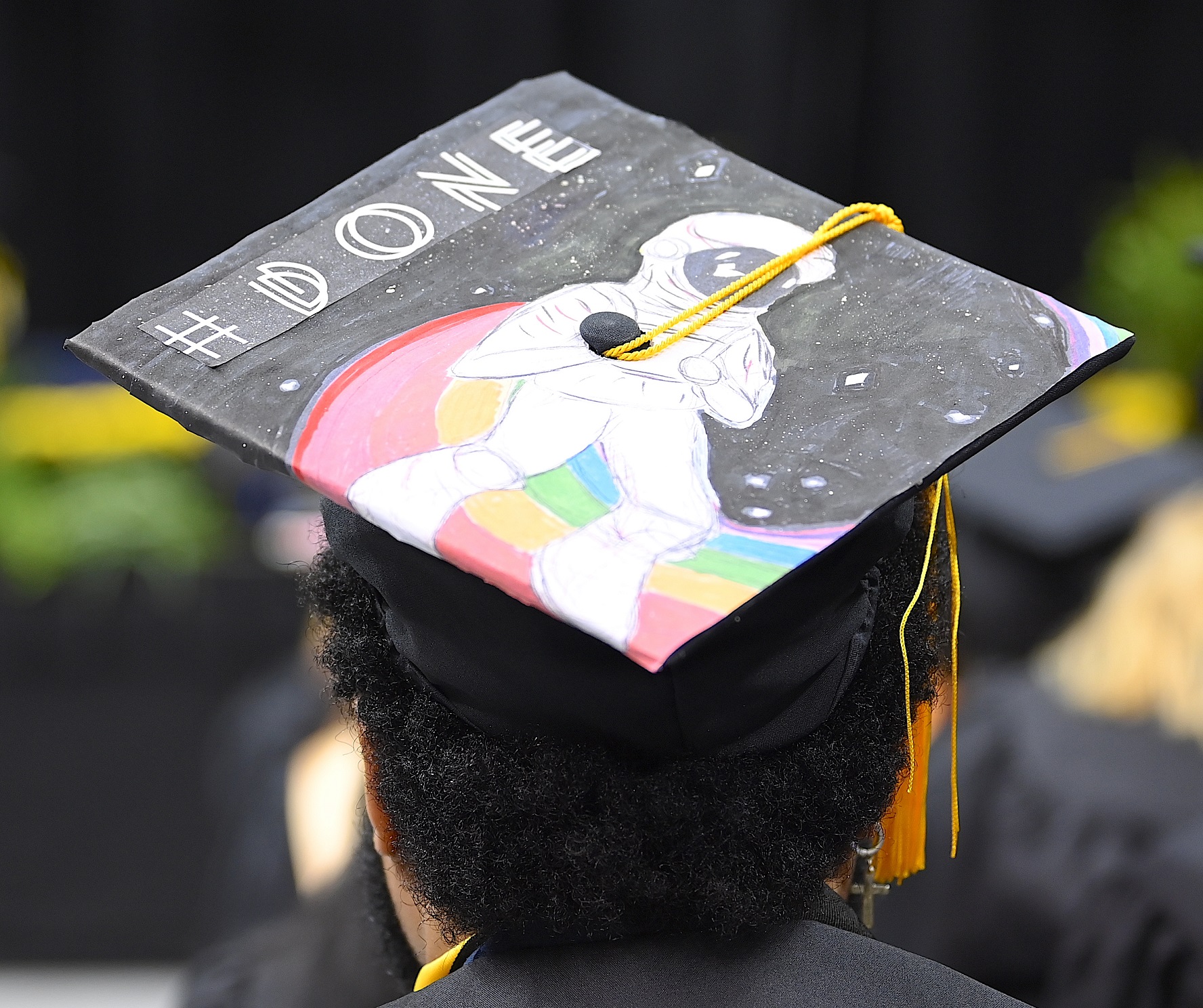 A graduation cap with a picture of an astronaut standing on a rainbow. The caps says "#DONE."