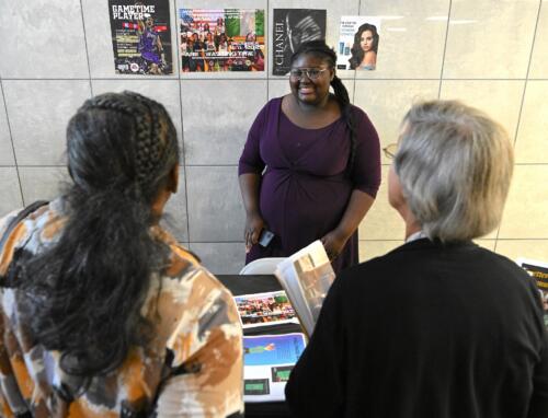 A graduate talks with women at her table about her portfolio.