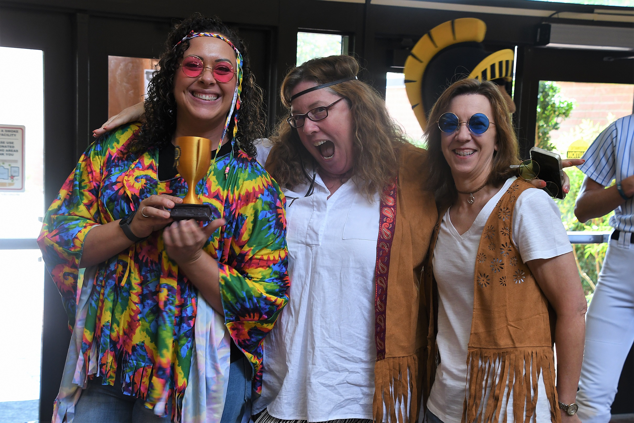 FTCC Foundation staff, dressed in 1960s outfits, hold a trophy for winning the costume contest.