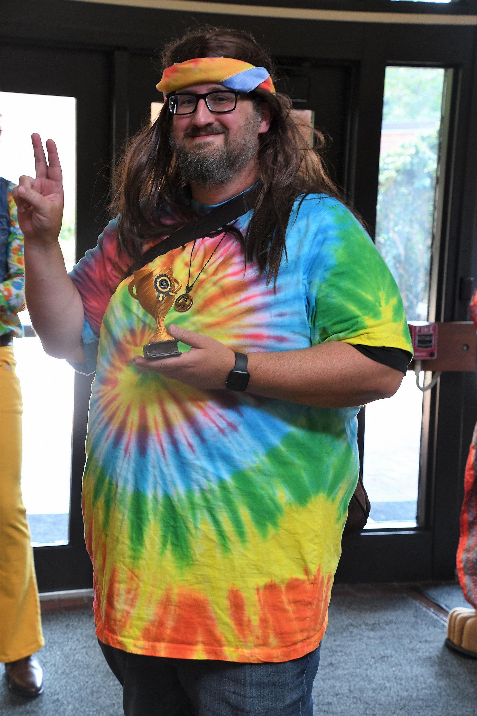 FTCC history instructor Christopher Thrasher, dressed in a tie-dyed shirt and a long wig, holds a trophy for winning the costume contest.
