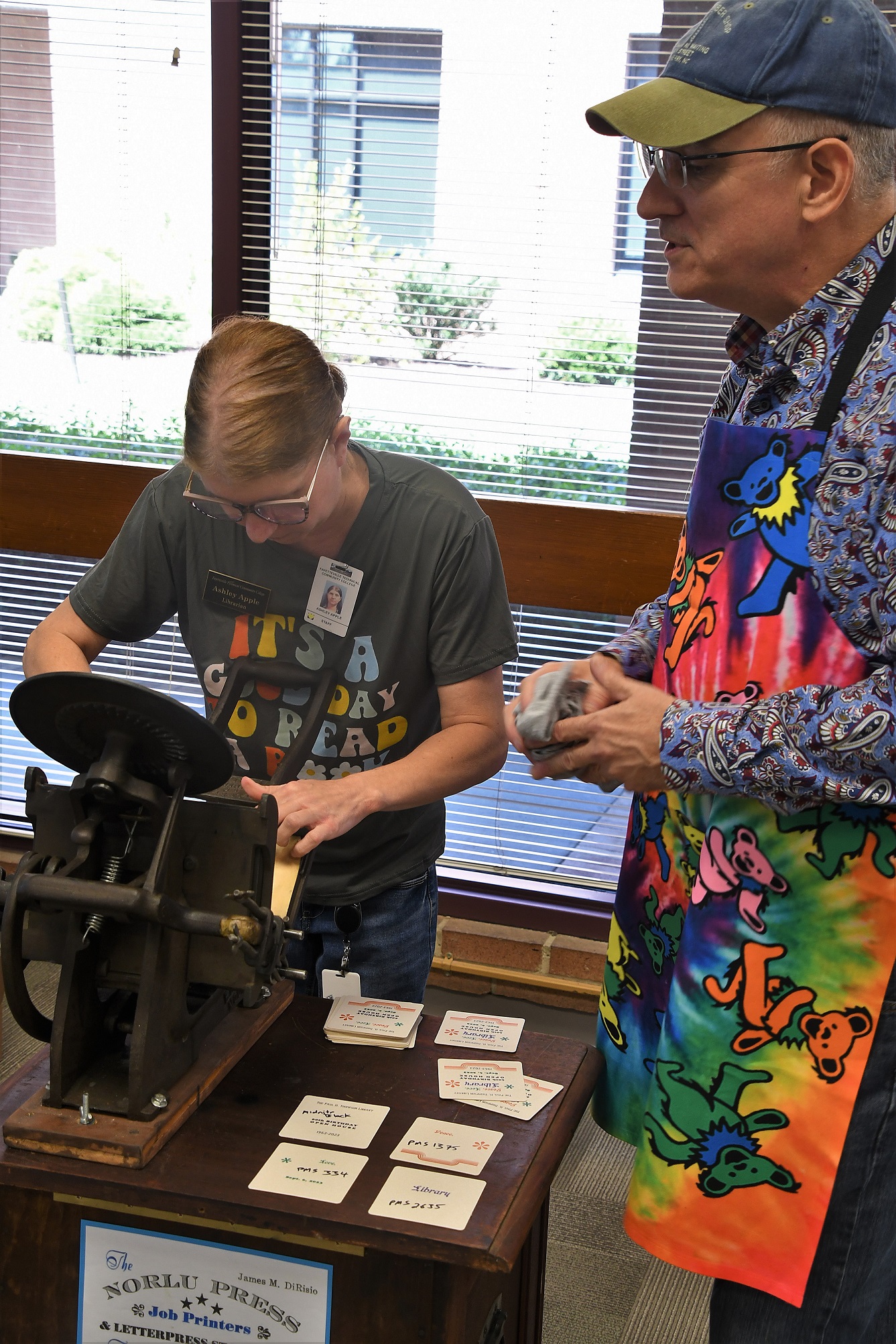 The Norlu Press owner James DiRisio, at right, helps library assistant Ashley Apple use a letterpress. 