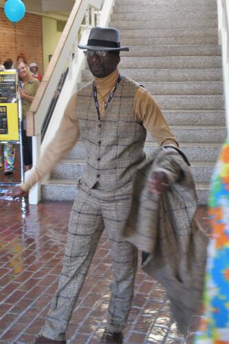 Athletics staffer Roderick Gooden, dressed in a 1960s-era suit, walks to the center of the library lobby.