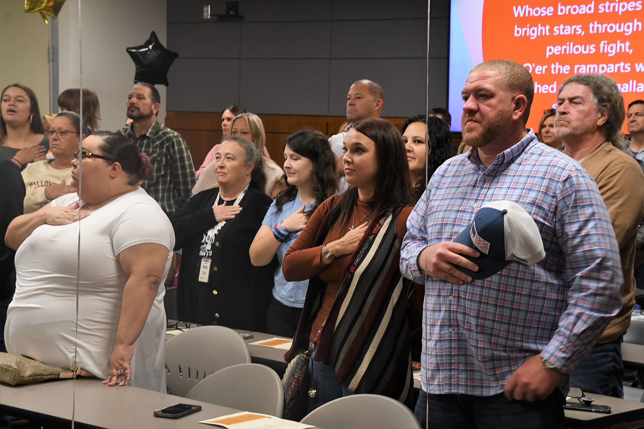 Audience members stand with their hands over their hearts during the playing of the national anthem.