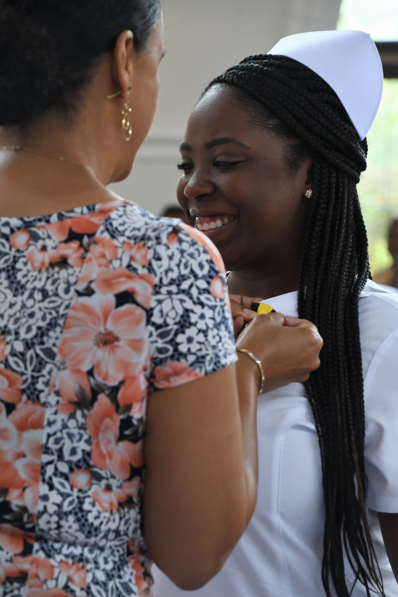 A close-up photo of a graduate smiling as she receives her pin.