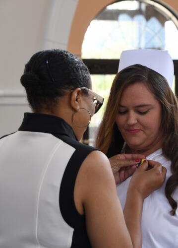 A graduate looks down as her pin is placed on her uniform.