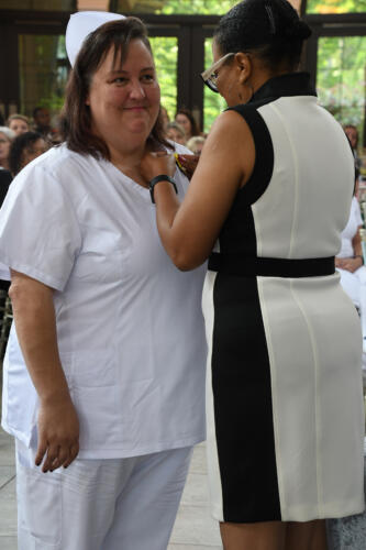 A graduate smiles as her pin is placed on her uniform.