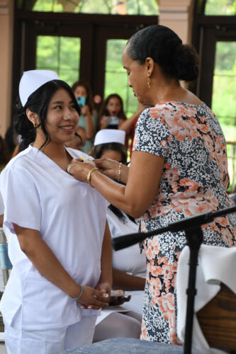 A graduate smiles as her pin is placed on her uniform.