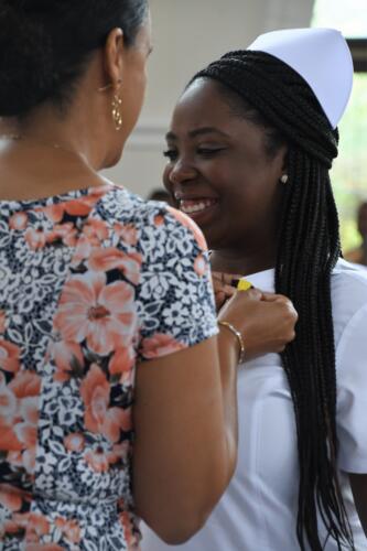 A close-up photo of a graduate smiling as she receives her pin.