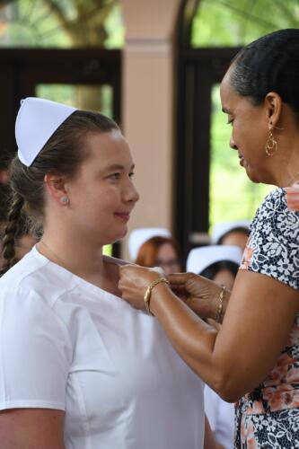 A graduate smiles as her pin is placed on her uniform.