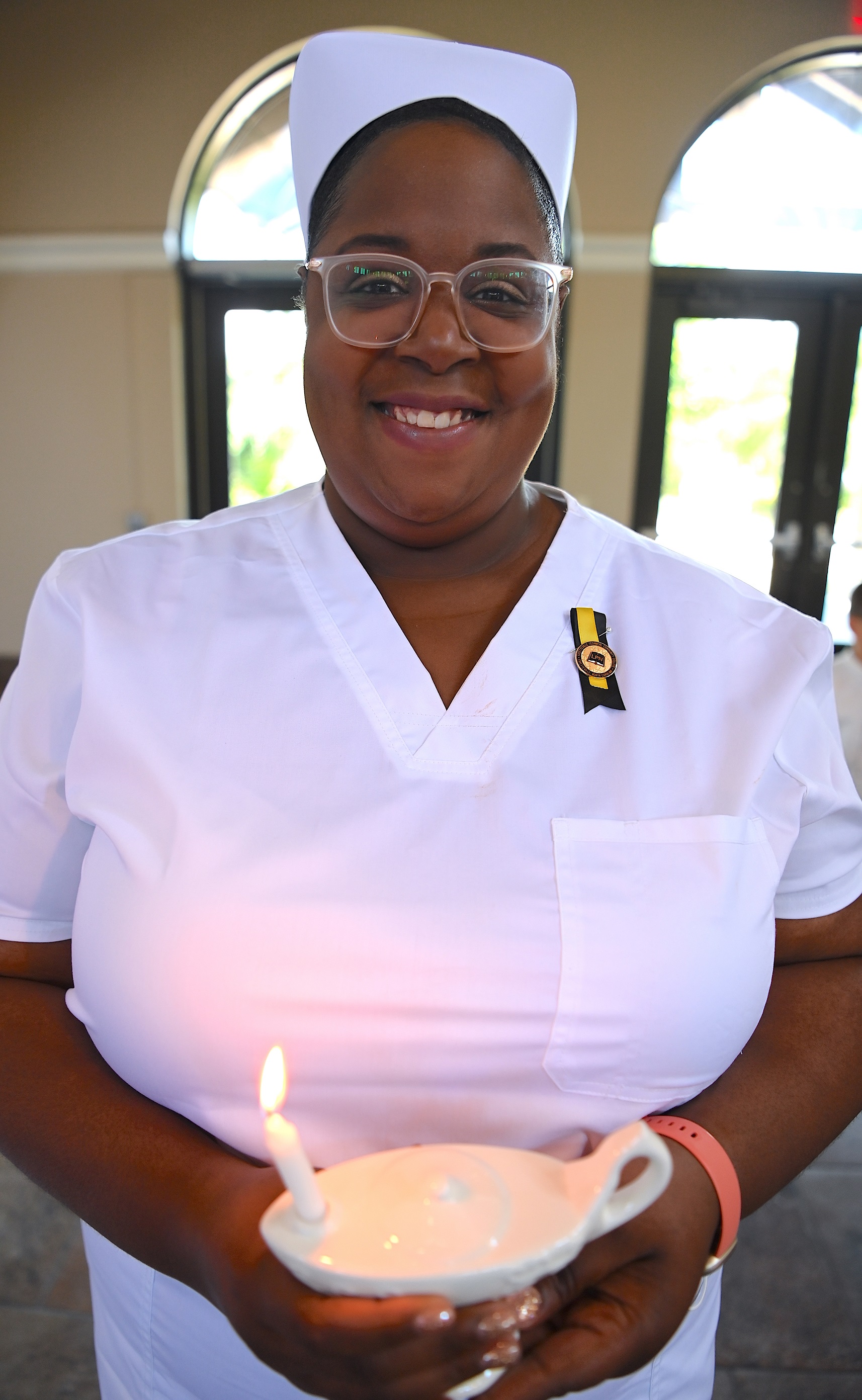 A close-up of a smiling nursing graduate holding her candle lamp.