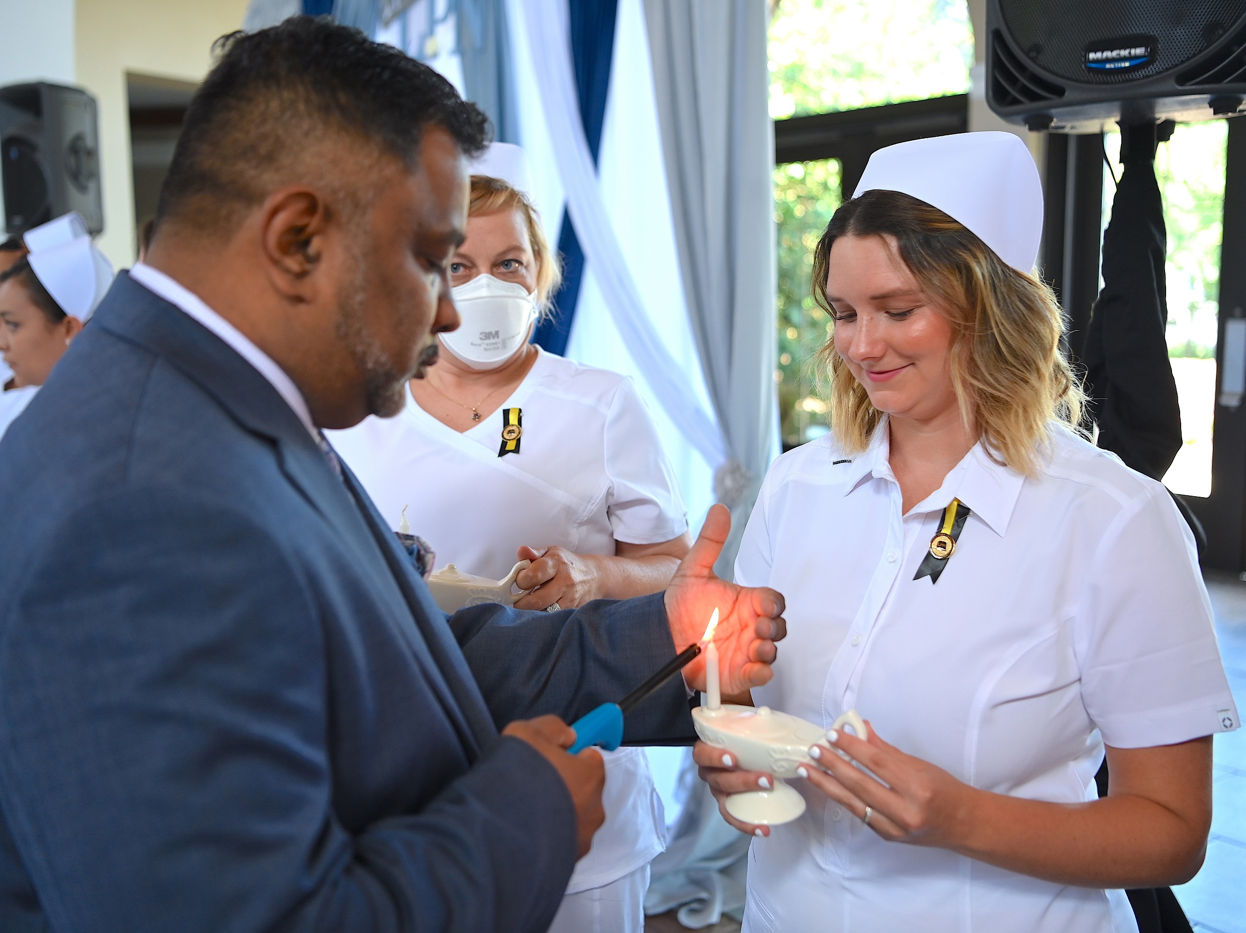 A graduate has her candle lamp lit.